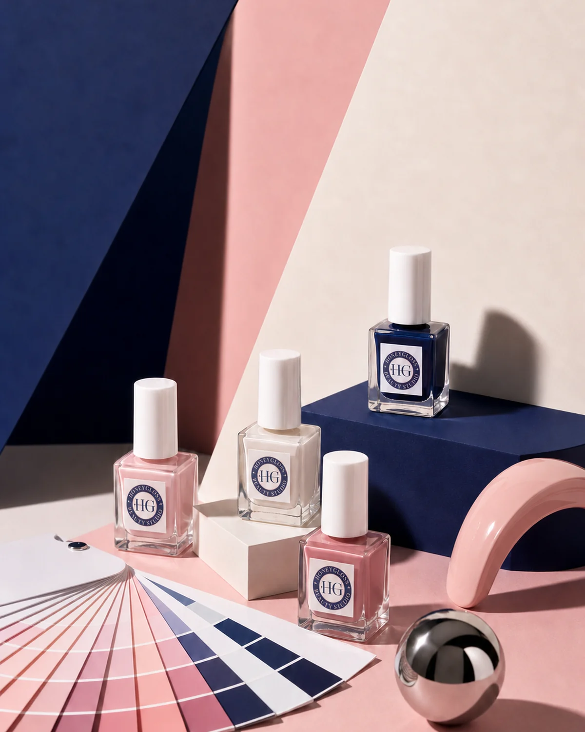 Bodegón editorial de esmaltes HoneyGloss y abanico de color en azul, rosa y blanco roto